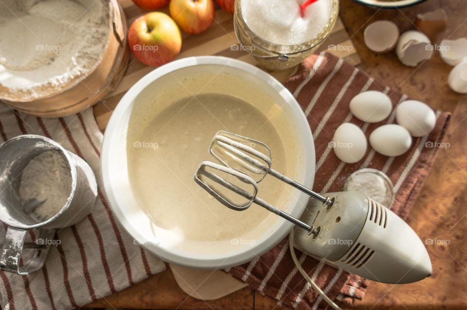 Making an apple pie dough using eggs, flour, sugar and apples.