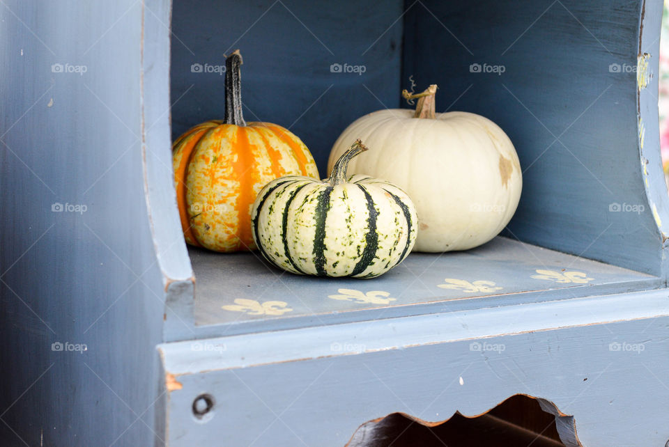 Assorted colored pumpkins on a rustic blue wooden shelf