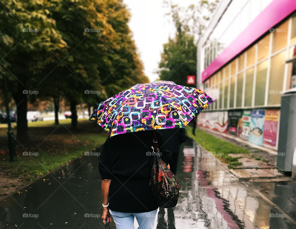 Walking with colorful umbrella under the rain 