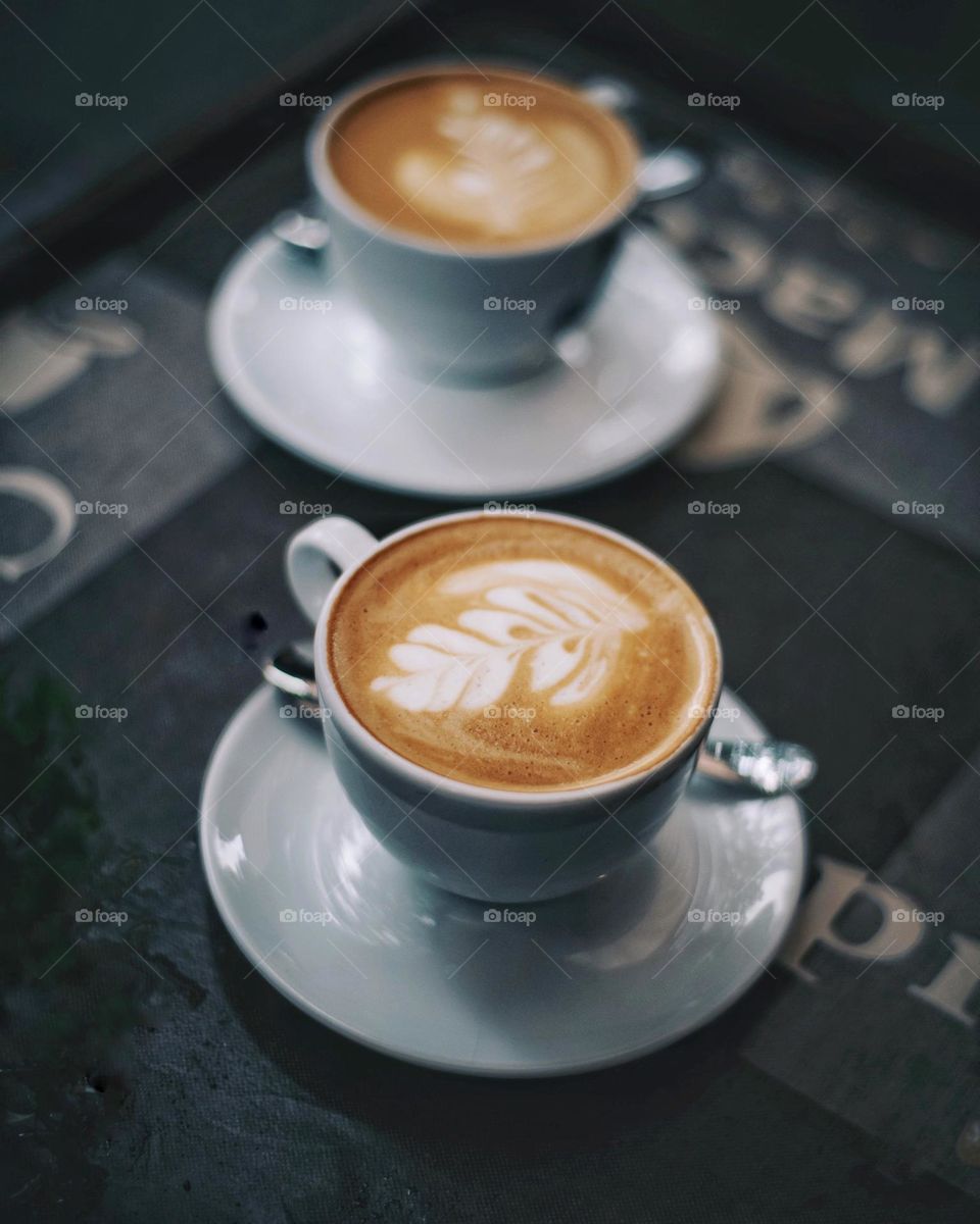 Coffee cups on the table with coffee and latte art. In a cafe, coffee photography, white coffee cups
