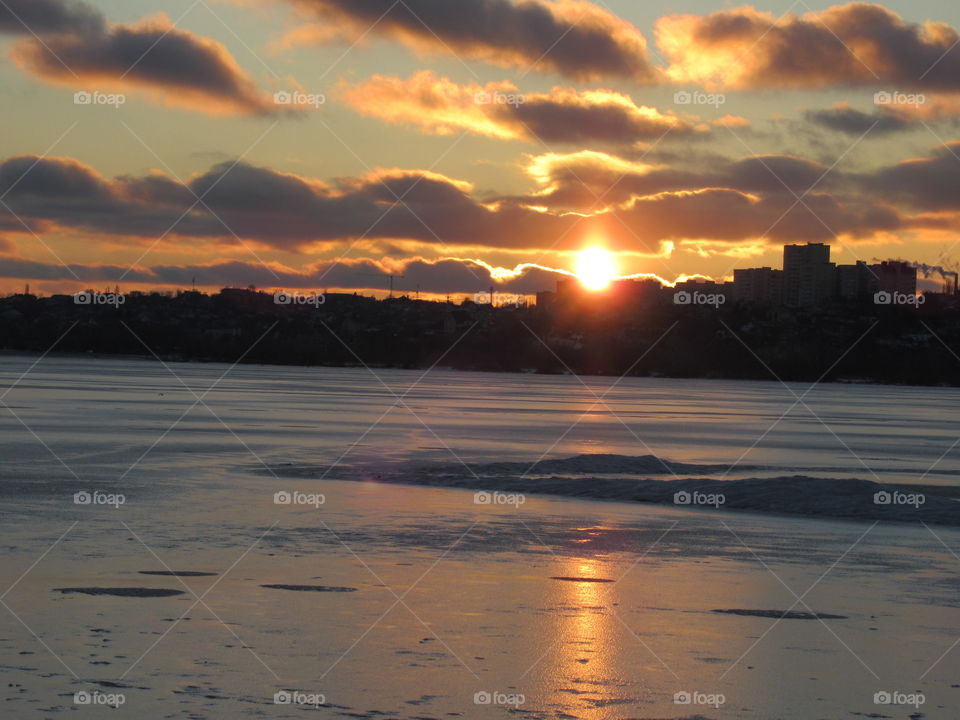 frosty evening in February, sunset and the sky in the clouds, I like to look at the sun going beyond the horizon in winter
