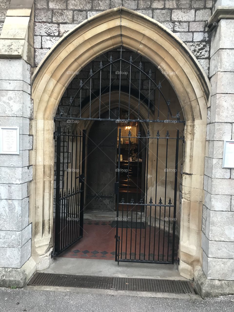 All Saints Church, Torquay, the gated entrance, the electric light in the distance, depicting a service in progress.