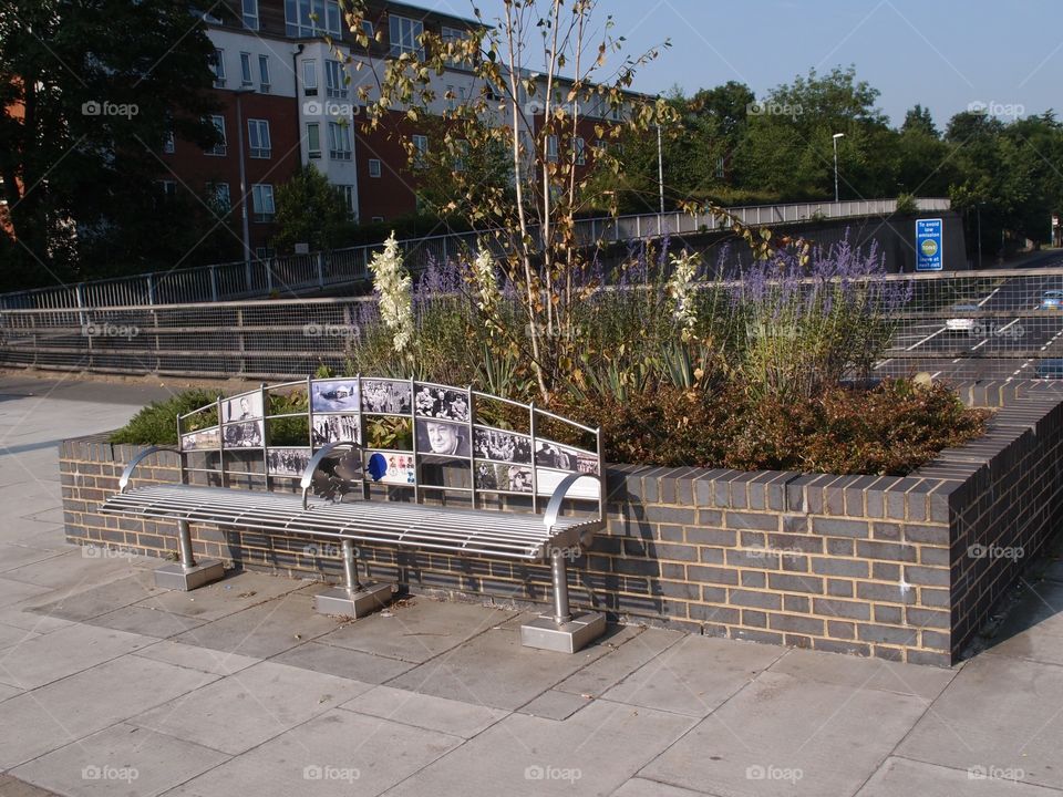 A nice bench awaits walkers on an overpass straddling a freeway. 