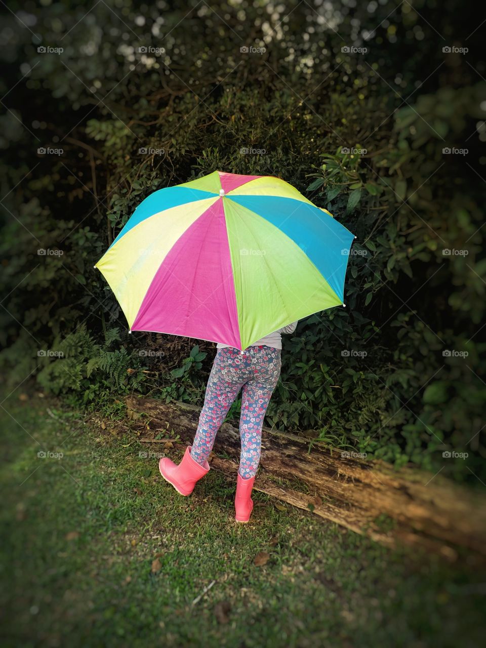 Girl with colorful umbrella and pink rain boots.