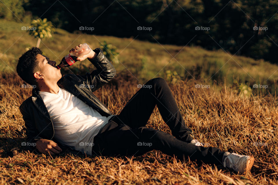 Boy enjoys a delicious Coca Cola in a hot sunrise in the middle of the mountain