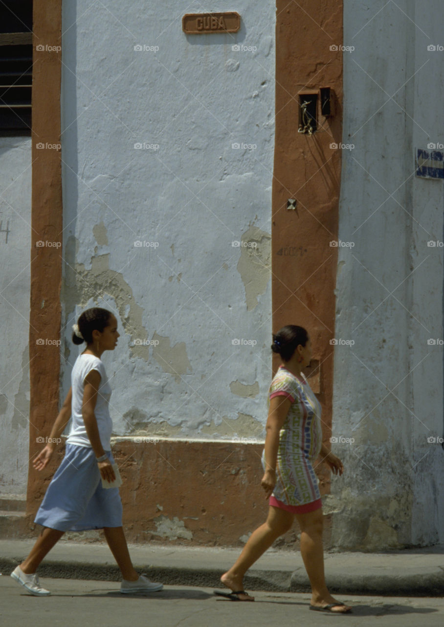 Mother and daughter walking down Cuba Calle in Havana, Cuba. Paint may be peeling off the walls and street lights don't always work in Old Havana but there are plenty of photo opportunities for street photographers with an eye for the candid shot.