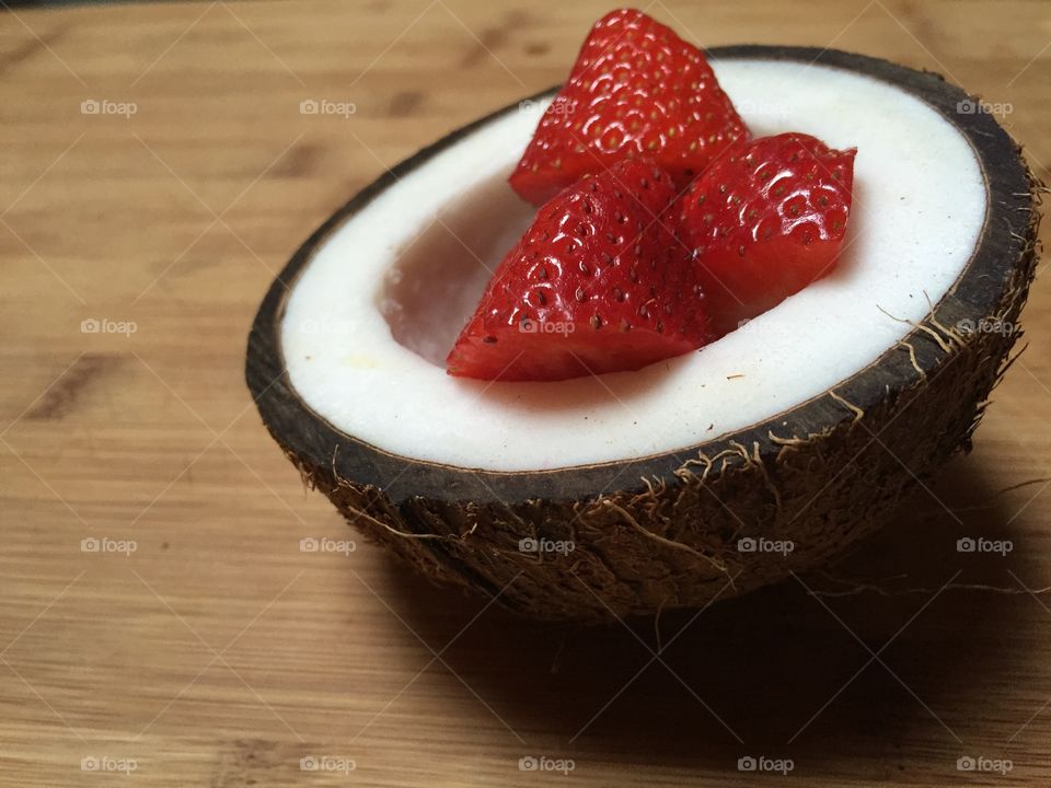 Strawberries in a coconut bowl on wooden table
