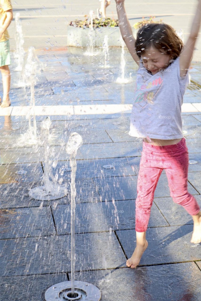 Girl getting wet and refresh at city fountain 