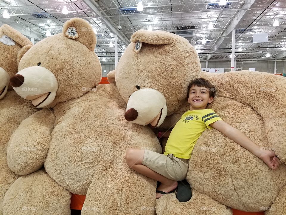 Smiling boy sitting on teddy bear