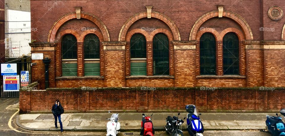 Man waits for a taxi next to a lineup of scooters on a gloomy day in London 