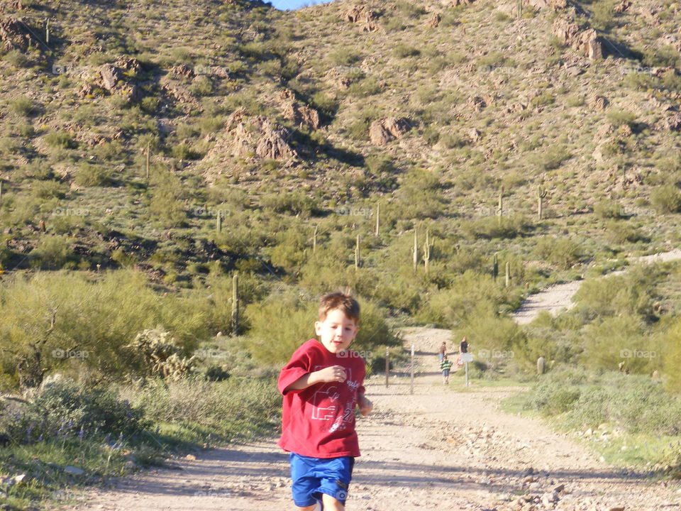 Little boy running back down a trail.