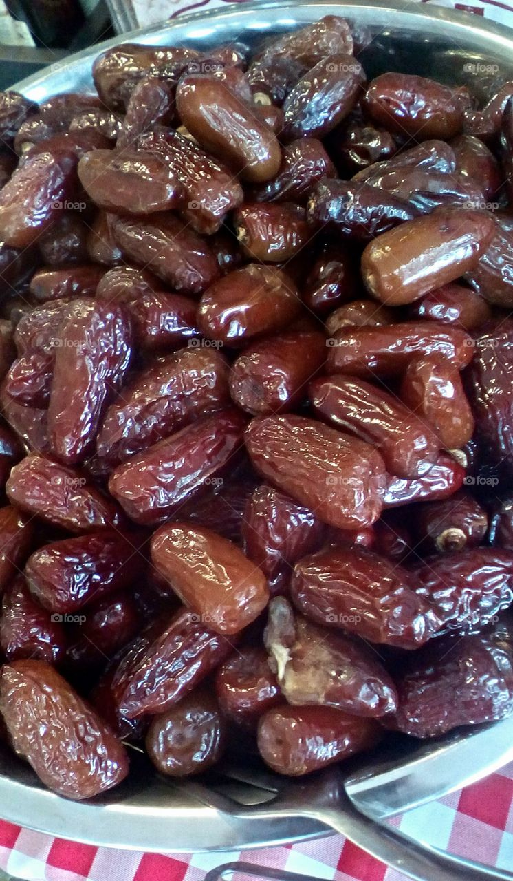 Abundance of dry sweet tropical healthy
exotic dates fruit in a big round bowl
in store for sale in closeup