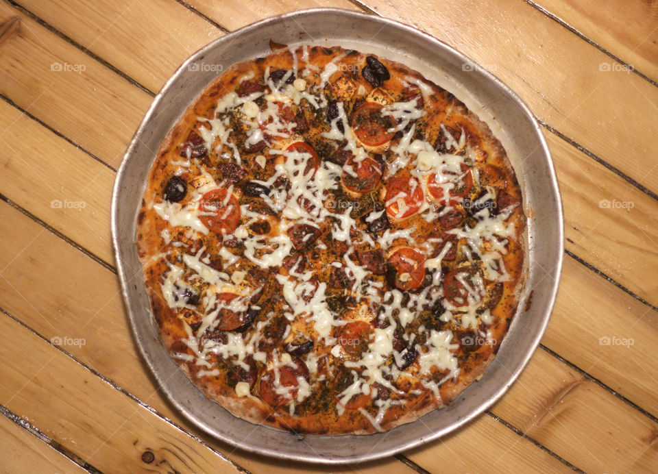 Roun metal cooking tray with pizza on wooden background