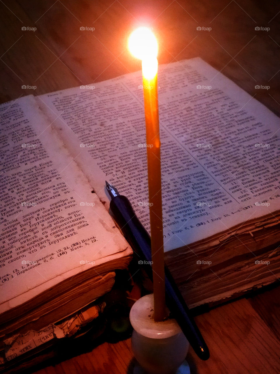 Old book, ink pen and a candle that burns