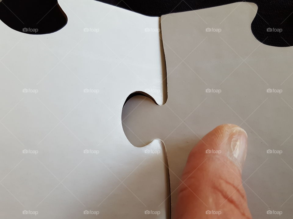 Close-up of human finger with puzzle pieces