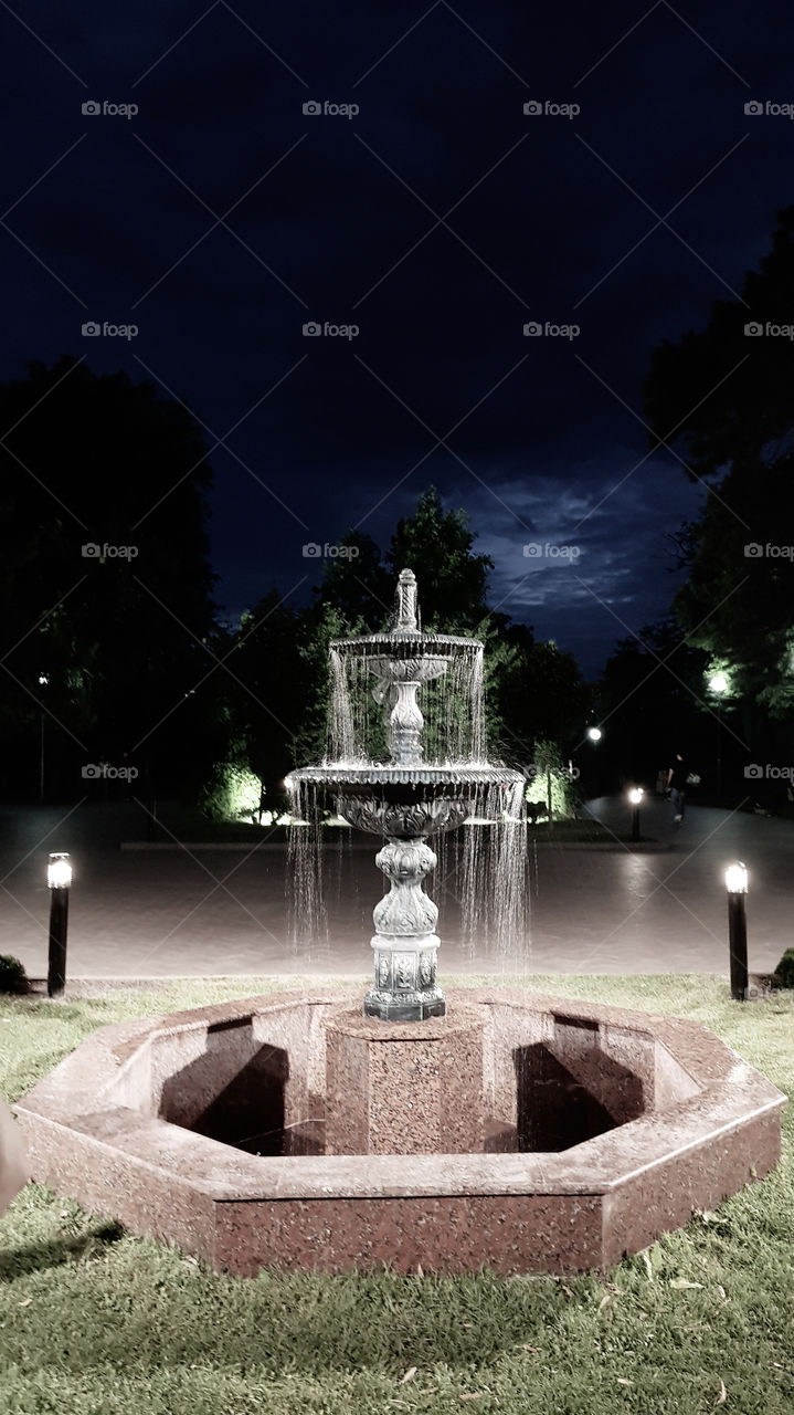 Beautiful view to fountain and lights in the evening park.