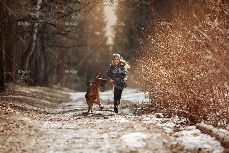 Girl walking with German shepherd puppy in a spring forest 