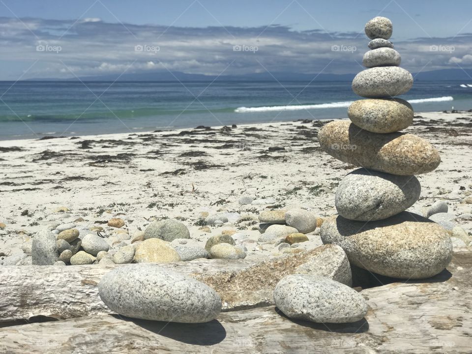 The pebbles from pebble beach stacked one on top of another, balancing as the waves crash on the shore. 