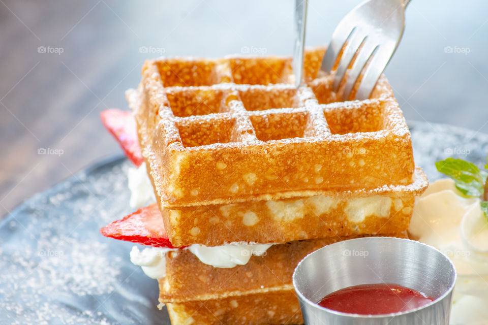 Waffle Strawerry fresh cream in the black plate on wooden table.