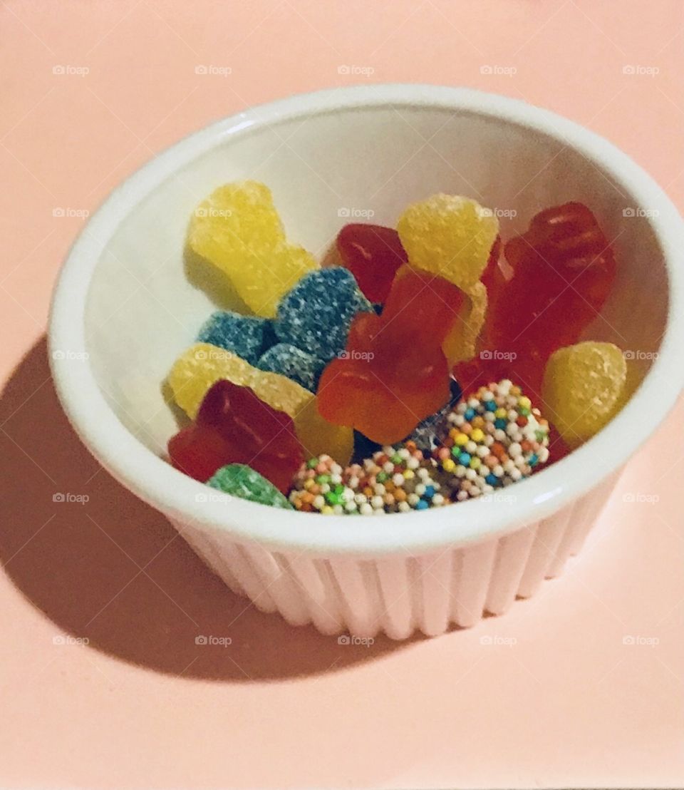 Rainbow colored candy in a white container 