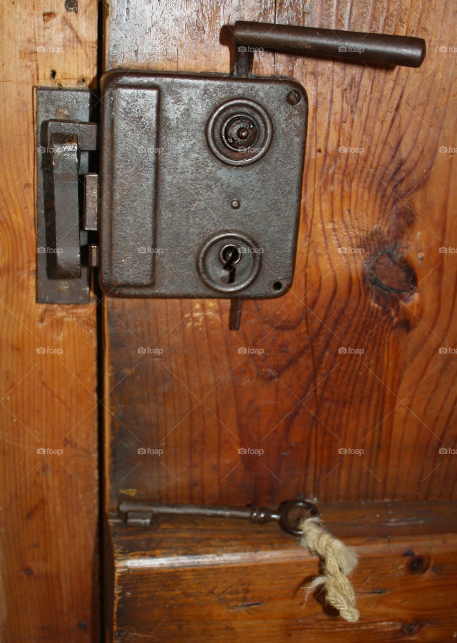 An old lock and an old key. 
Rustic, wooden door