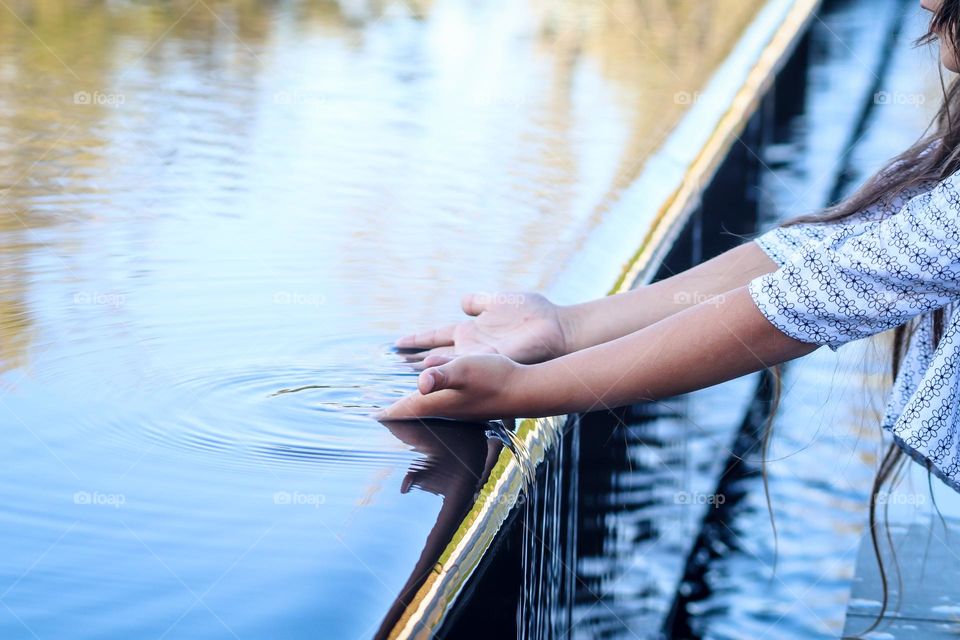 Child's hands in water of a fontain