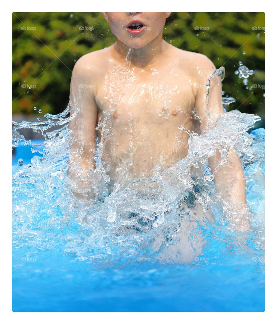 A big splash when a boy jumps into the swimming pool