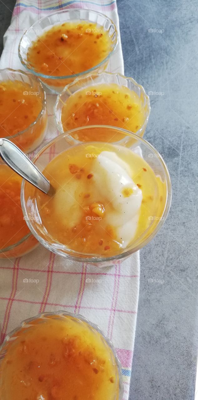 A delicious dessert made of milky custard and cloudberry kissel one on the other in the glass bowls.