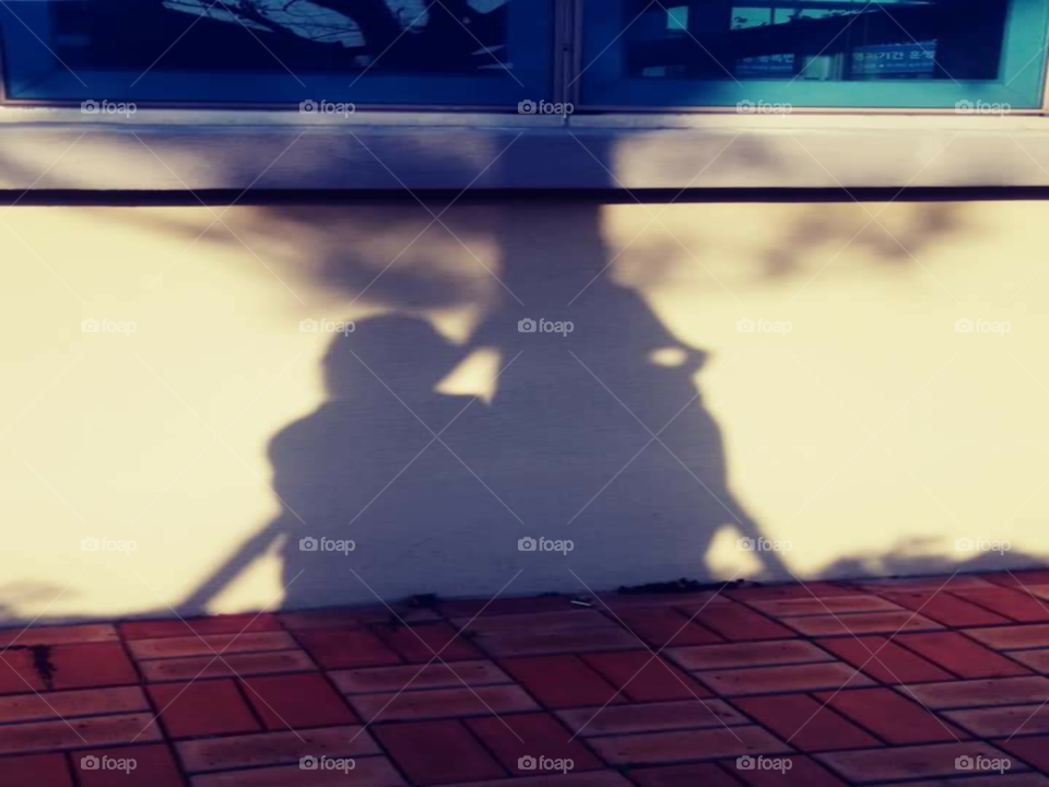 a shadow of a mother and child who's  talking each other  face to face infront of the carabao tree.