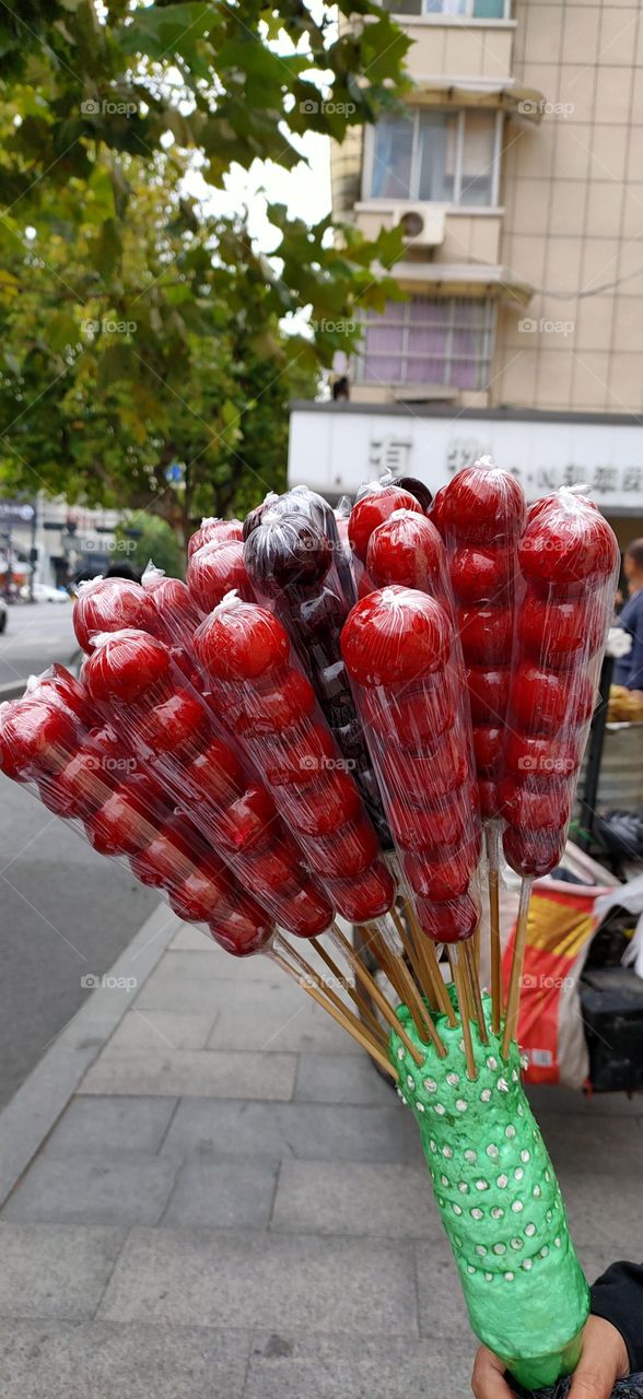 These are sugar-coated haws, or “Bingtang Hulu” in Chinese. Sugar-coated haw is a traditional snack of Beijing. As a local, you used to see peddlers selling sugar-coated haws on streets and lanes.