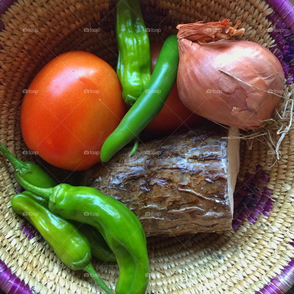 Basket of vegetables- yuca root, shallot, peppers, tomatoes, and chile. 