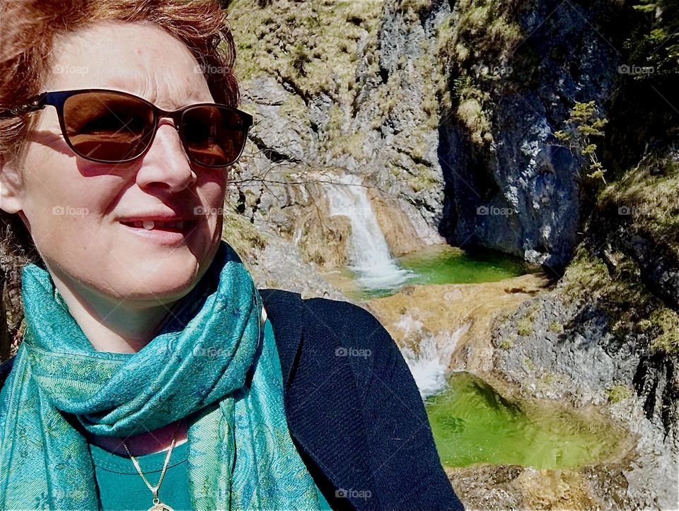 Telling from her smile this young lady is enjoying her trip to the local waterfall by „Bayerischzell“, a small town near the Alps in „Bavaria“, Germany tremendously. 2024. Hypnotic Productions