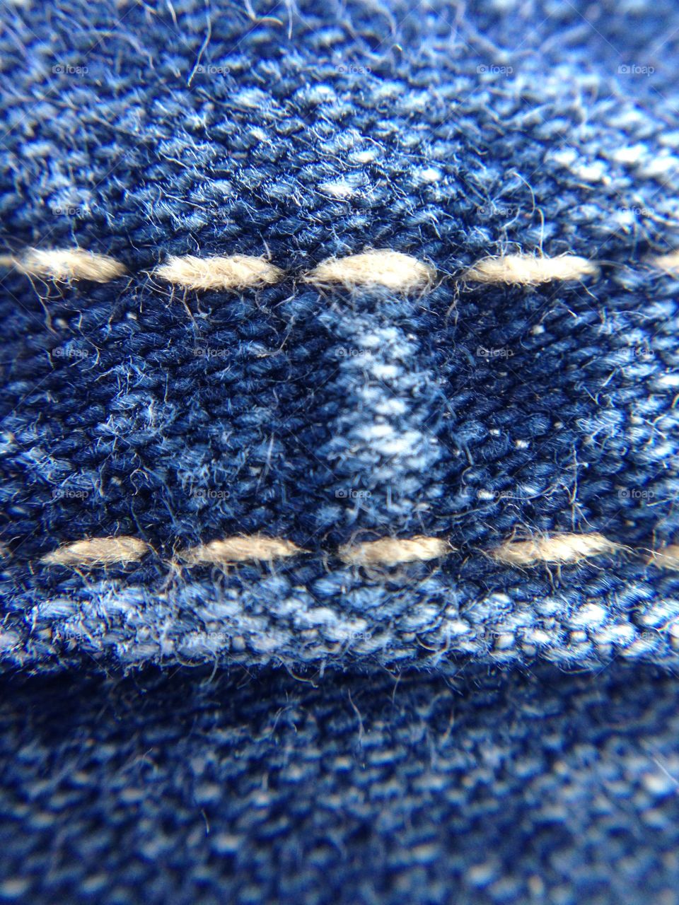 Hem of blue jeans. Every string is easily seen. 