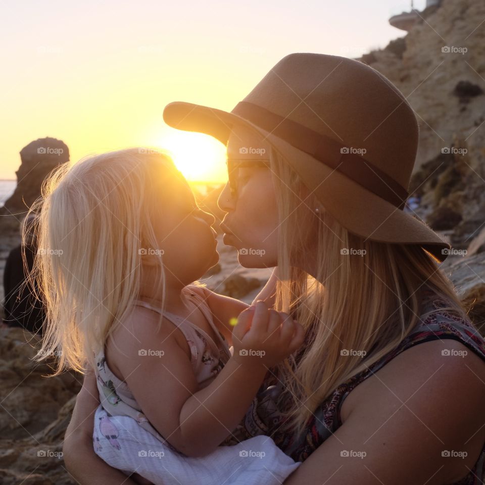 Mother and daughter kissing at sunset on the beach. 