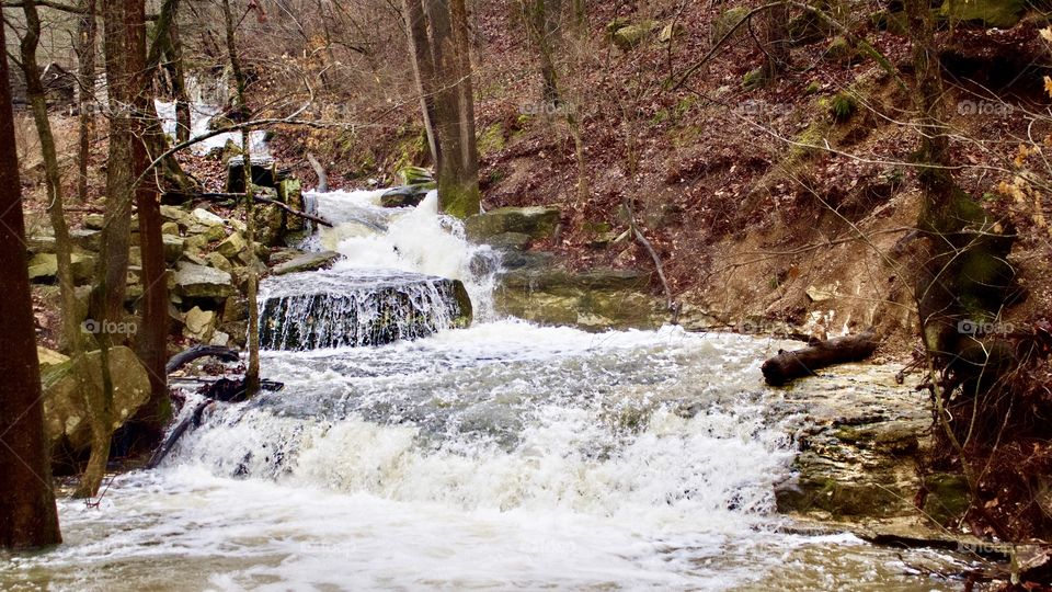 Water cascades down a stunning natural rock spillway at Black Bass Lake in Eureka Springs, Arkansas.