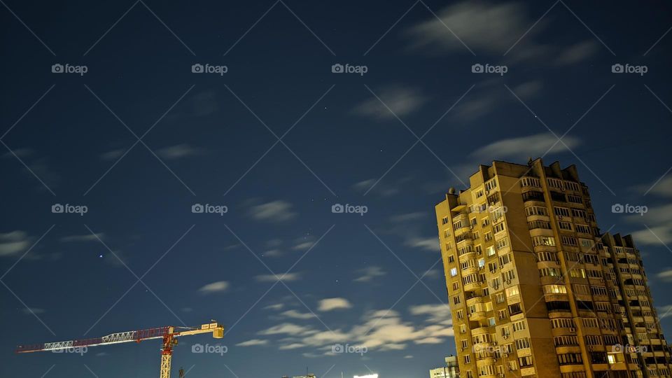 night sky with clouds and stars on the background of a residential building