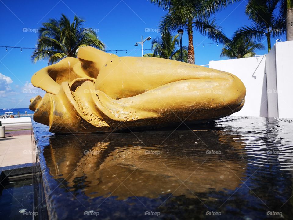 fuente de un coracol mujer, fusión un tanto perturbadora pero bellísima, donde el dorado con negro crean un gran contraste con el cielo y mar azules del malecón