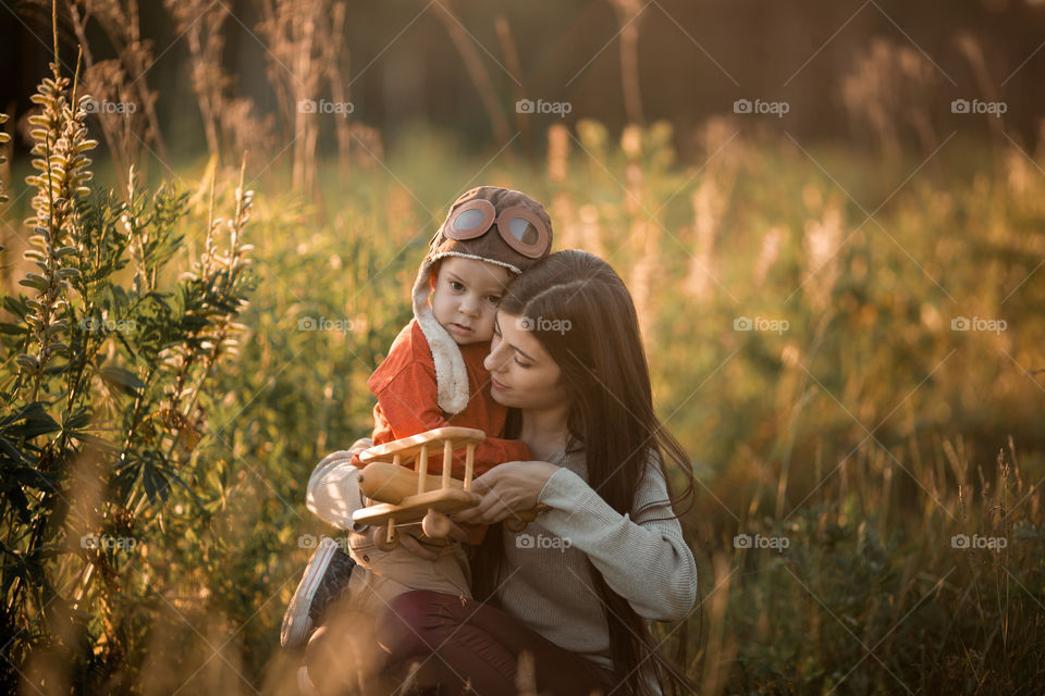 Mother and son with wooden plane at sunset