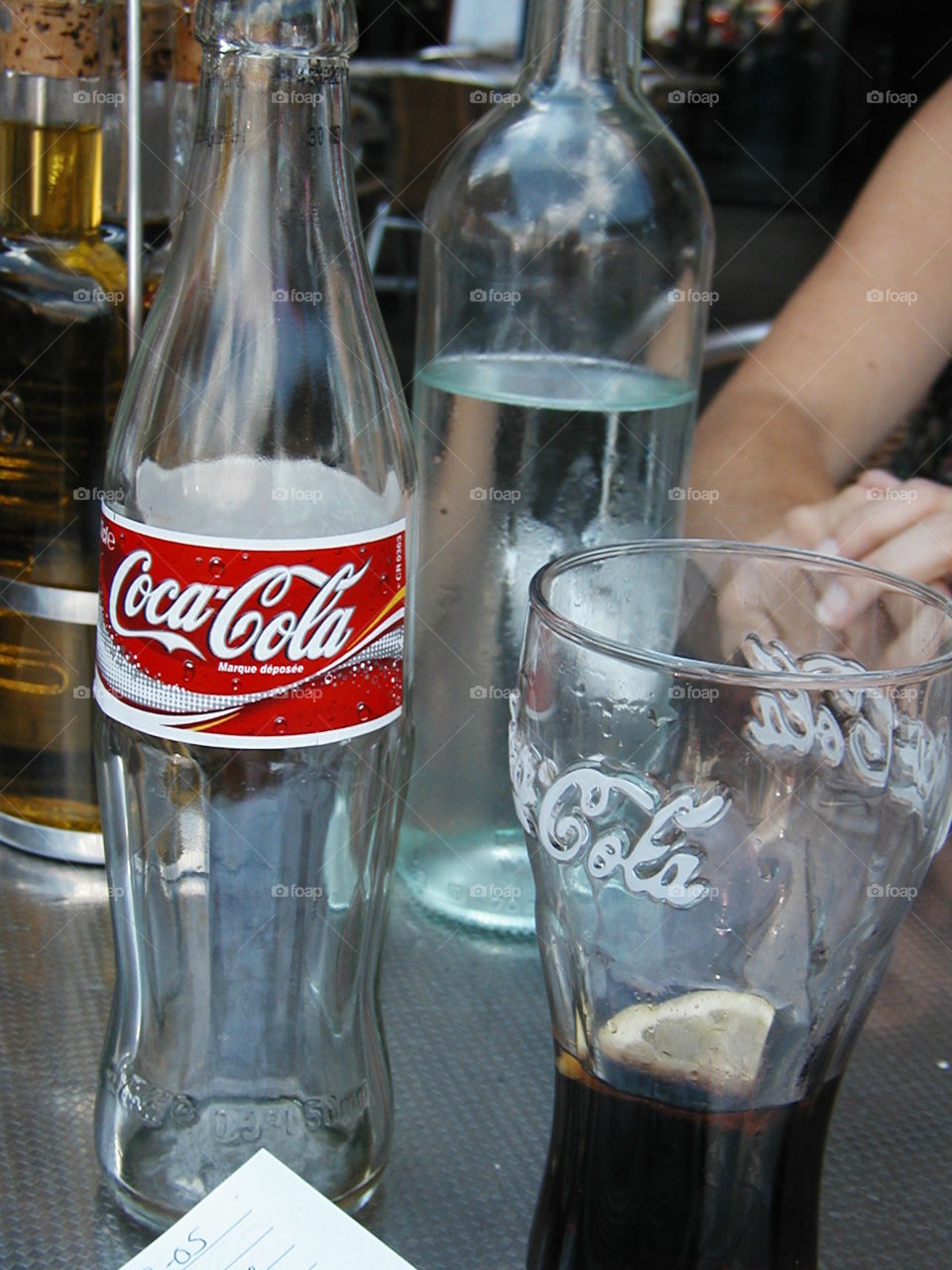 Coca-Cola refreshment . A bottle of Coke and a coke glass at an outdoor cafe in France