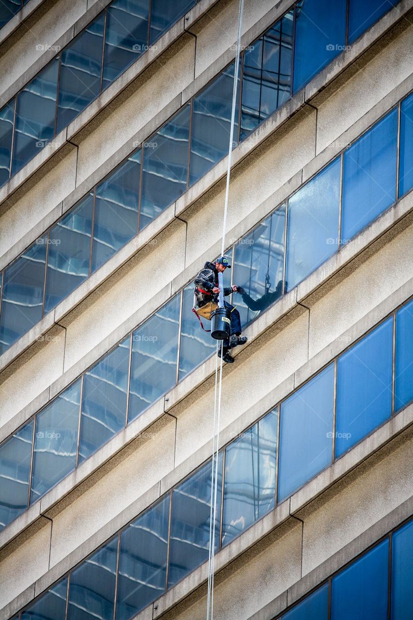 Man is washing windows on a skyscraper