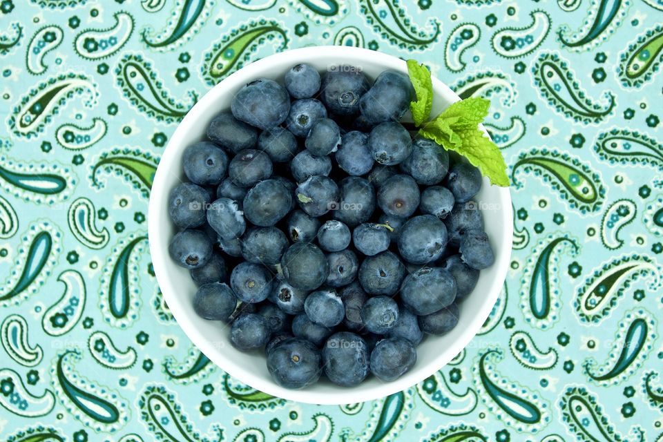 Fruits! - Blueberries and a spring of mint in a white bowl on teal and green paisley fabric