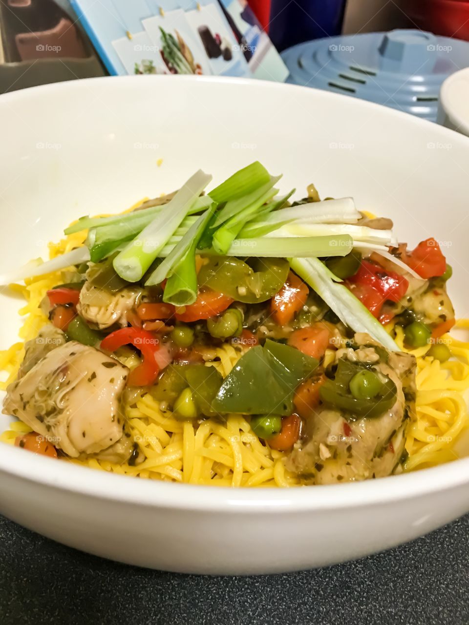 Closeup view Thai chicken stir fry over pad noodles in bowl closeup 