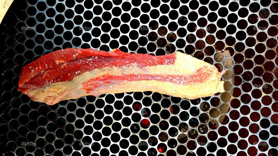 Manta de carne crua com sal grosso, em grelha, pra churrasco.