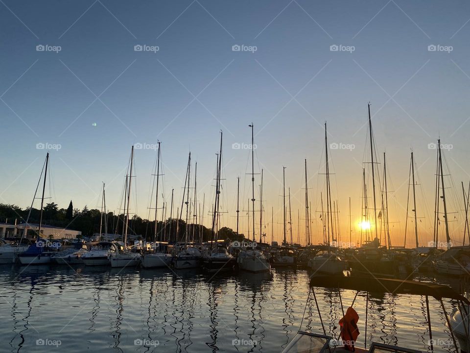 beautiful red summer sunset on the pier against the background of boats, yachts, ships