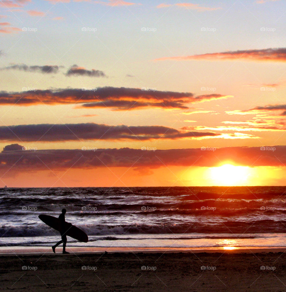 Surfer on the beach at sunset 