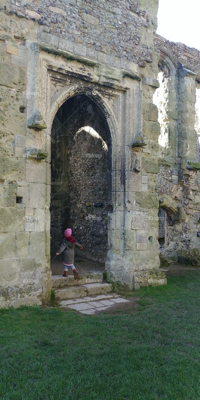 small girl entering doorway of old ruined castle