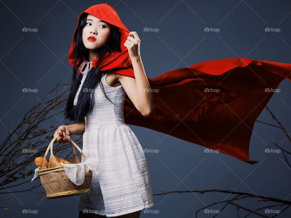 Girl in the little red riding hood costume running away from the wolf 