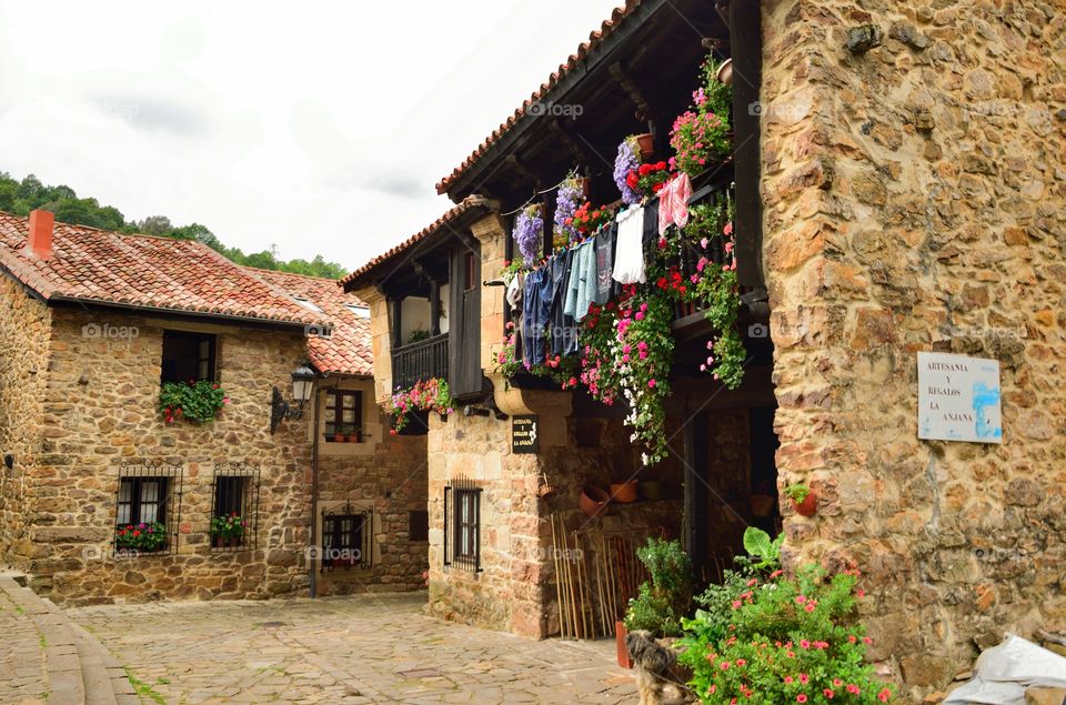 Clothes and flowers hanging from a balcony in Bárcena Mayor, Cantabria, Spain.