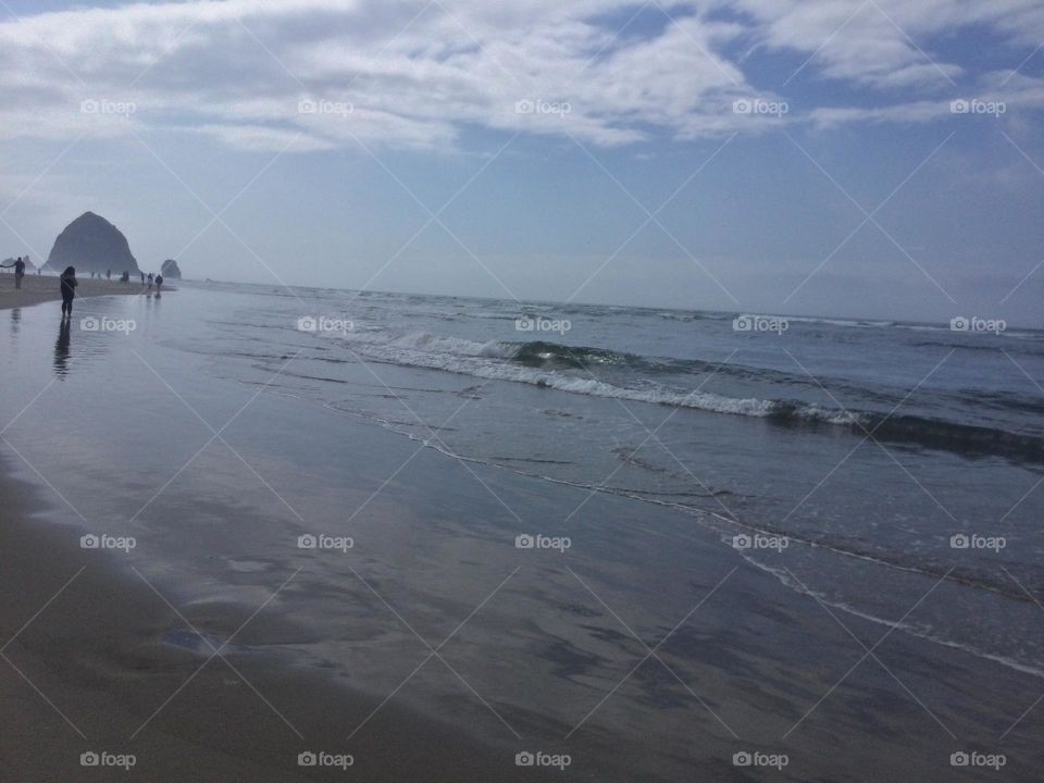 People Along Cannon Beach, Oregon with the Rock Formations in the Distance 