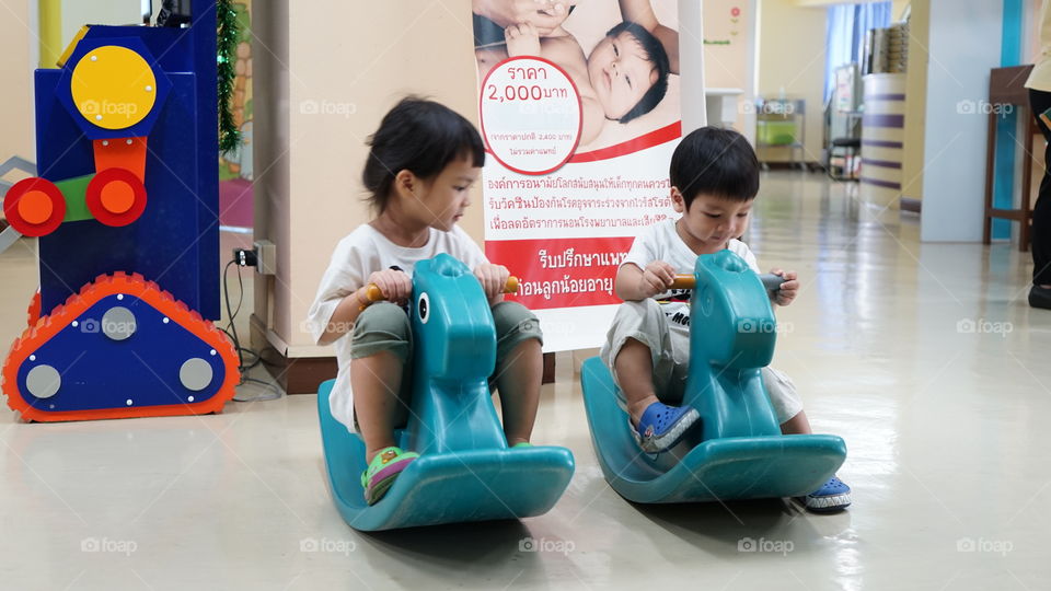 Asian children riding on a playground